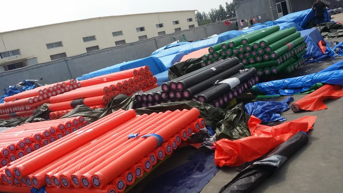 Rouleaux emballés en orange, noir et vert, disposés dans une cour.