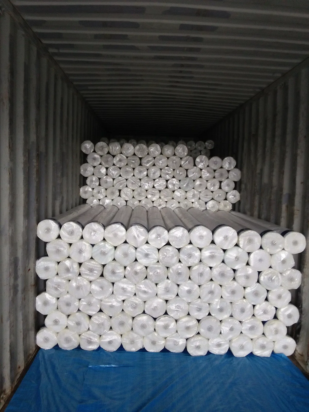 Rouleaux emballés en blanc et empilés dans un conteneur.