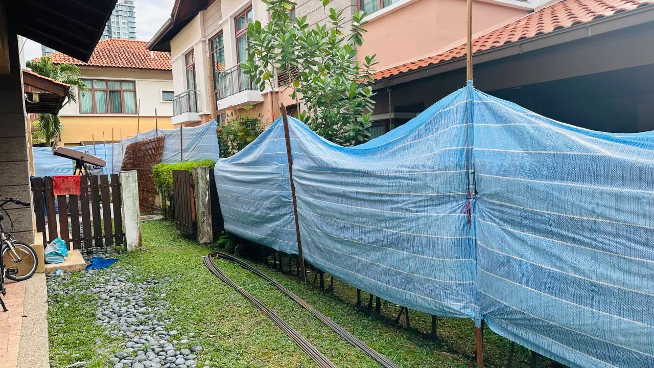 Lona a rayas azules y blancas fijada a soportes verticales junto a edificios residenciales.